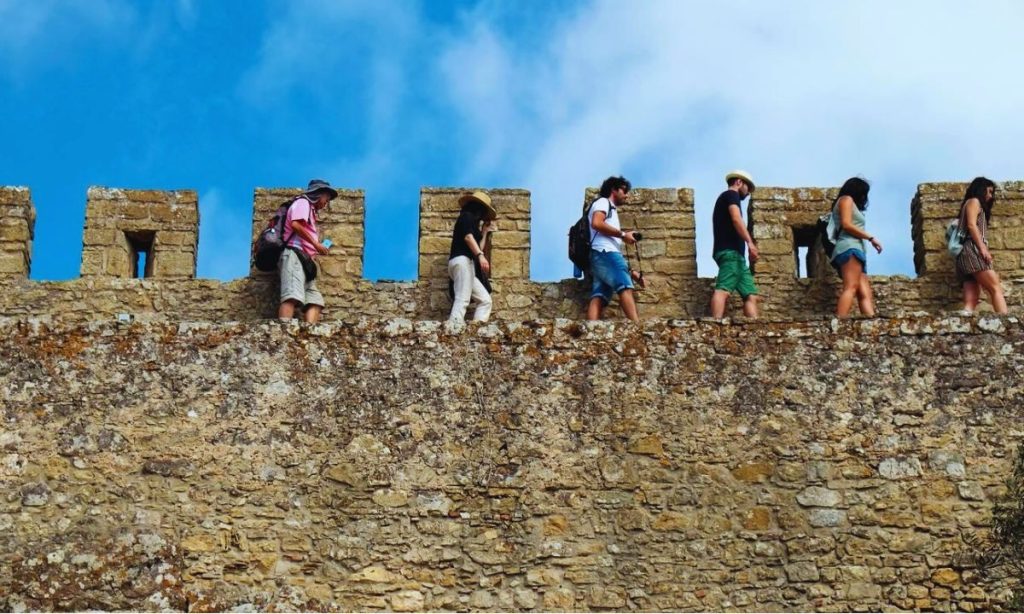 Tourists walk along the walls encircling the medieval town of Obidos, in Portugal